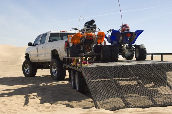 Quad bikes on trailer behind pickup truck in desert